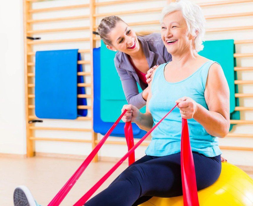 Senior woman with stretch band in fitness gym